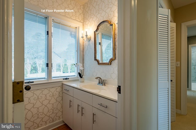 bathroom with a closet, vanity, and wallpapered walls