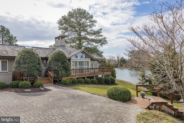 view of front facade featuring a deck with water view and a front lawn