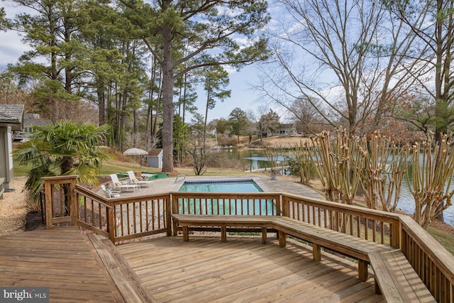 deck with an outbuilding, an outdoor pool, and a water view