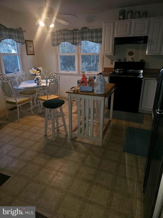 kitchen with ceiling fan, white cabinets, under cabinet range hood, tile patterned floors, and black electric range oven