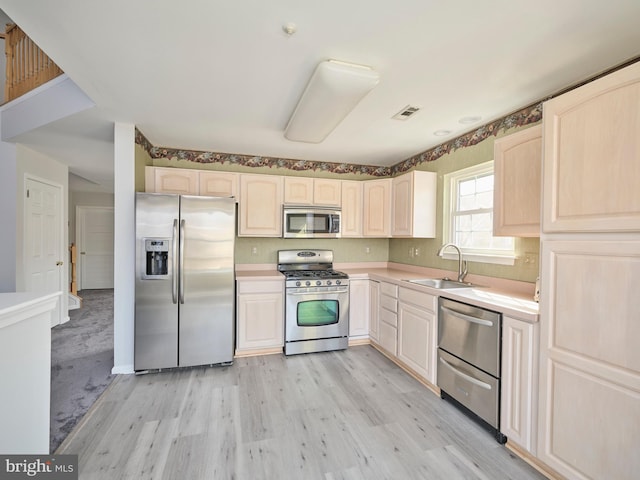 kitchen with a sink, light countertops, light brown cabinets, and stainless steel appliances