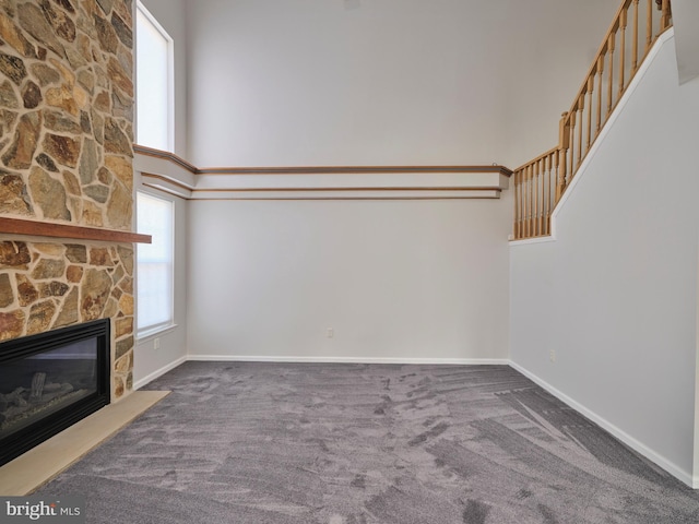 unfurnished living room featuring baseboards, a high ceiling, and a fireplace