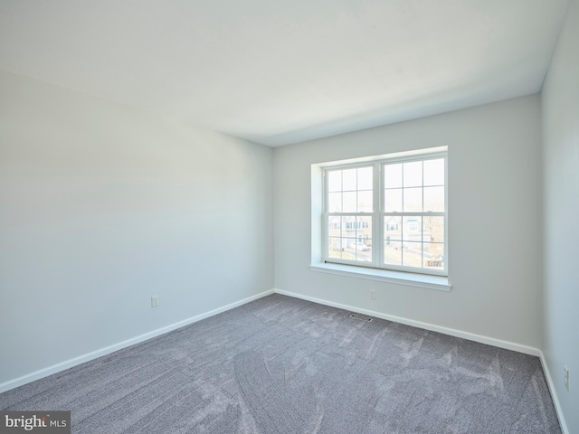 unfurnished room with visible vents, baseboards, and dark carpet