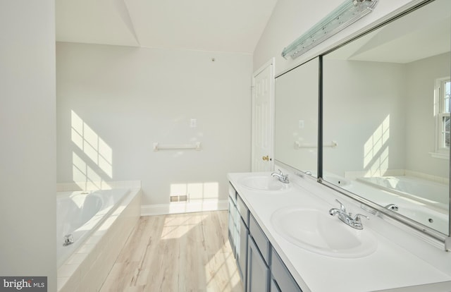 bathroom featuring a garden tub, double vanity, and a sink