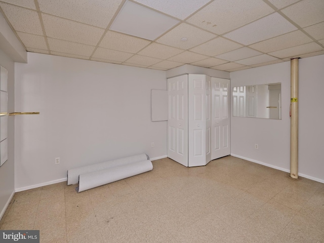 finished below grade area with tile patterned floors, a drop ceiling, and baseboards