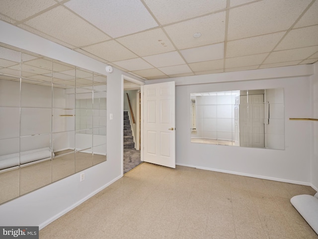 interior space with tile patterned floors, a paneled ceiling, stairs, and baseboards