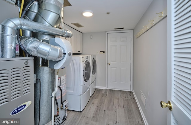 clothes washing area with light wood-style floors, visible vents, cabinet space, and independent washer and dryer