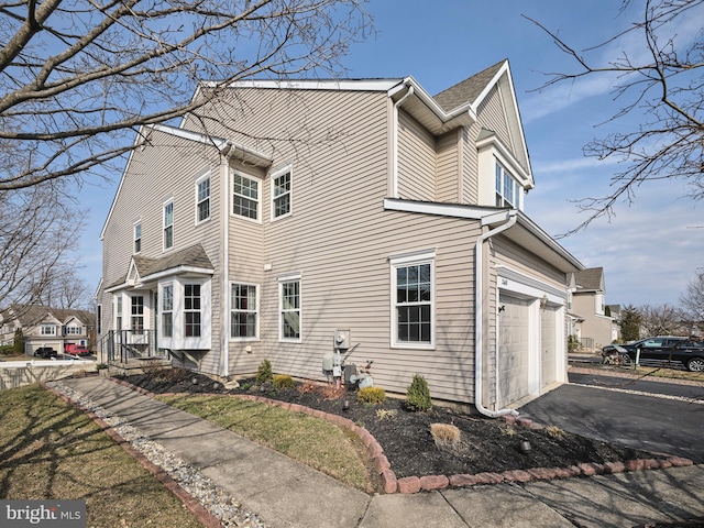 view of side of home with aphalt driveway and an attached garage