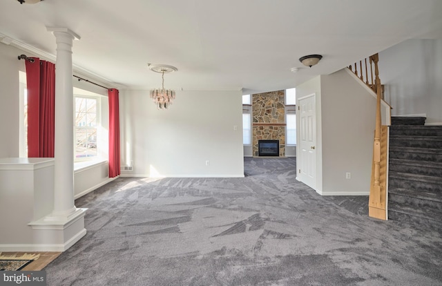 unfurnished living room featuring baseboards, stairway, carpet floors, decorative columns, and a stone fireplace