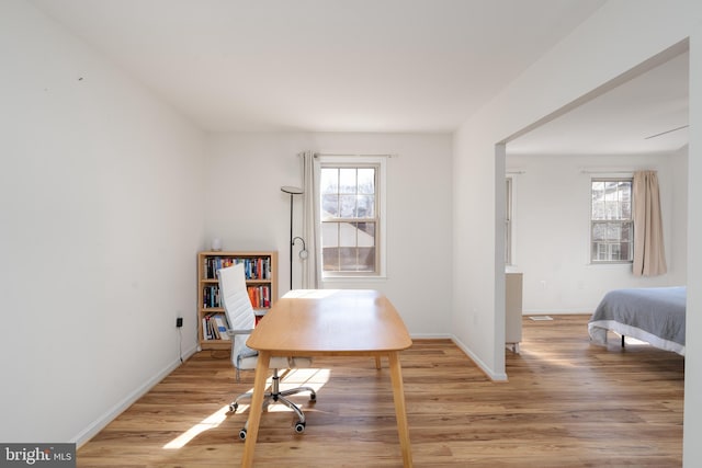 unfurnished office with a healthy amount of sunlight, light wood-type flooring, and baseboards