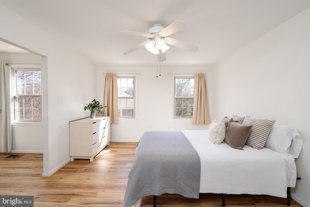 bedroom with baseboards, multiple windows, and light wood-style floors