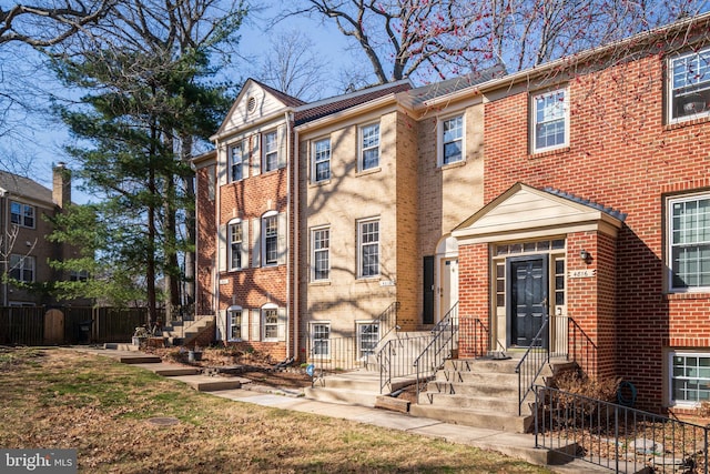 view of front facade with brick siding and fence