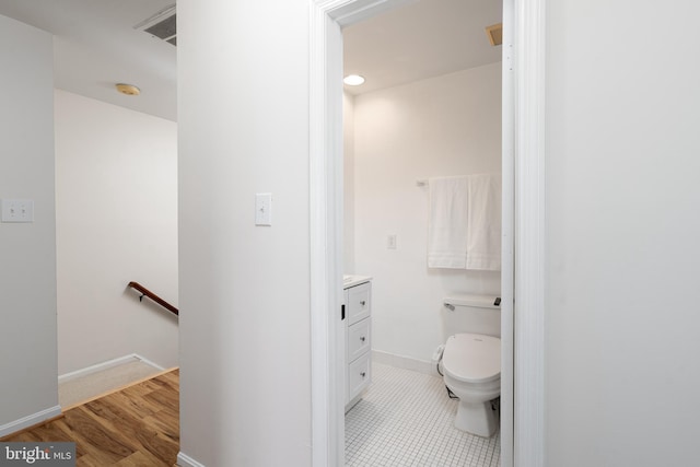 bathroom with baseboards, toilet, wood finished floors, and vanity