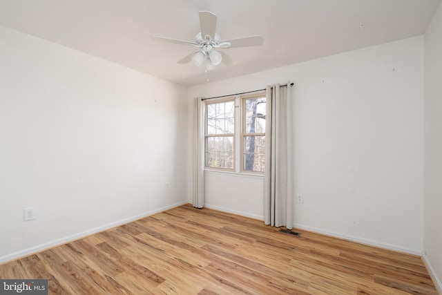 spare room featuring ceiling fan, visible vents, light wood-type flooring, and baseboards