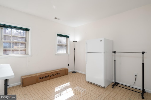 interior space featuring visible vents, baseboards, and freestanding refrigerator