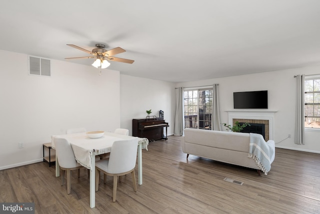 dining space featuring visible vents, light wood-style floors, and a brick fireplace