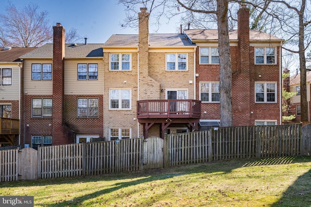 rear view of property featuring a yard, brick siding, and a fenced backyard