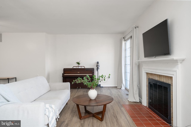 living room with a fireplace with flush hearth, baseboards, and wood finished floors