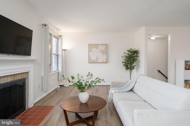 living room featuring a tiled fireplace and wood finished floors