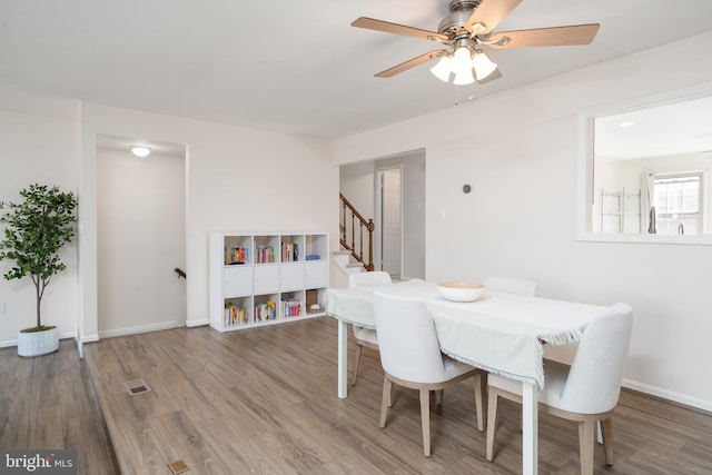 dining area featuring stairway, baseboards, and wood finished floors