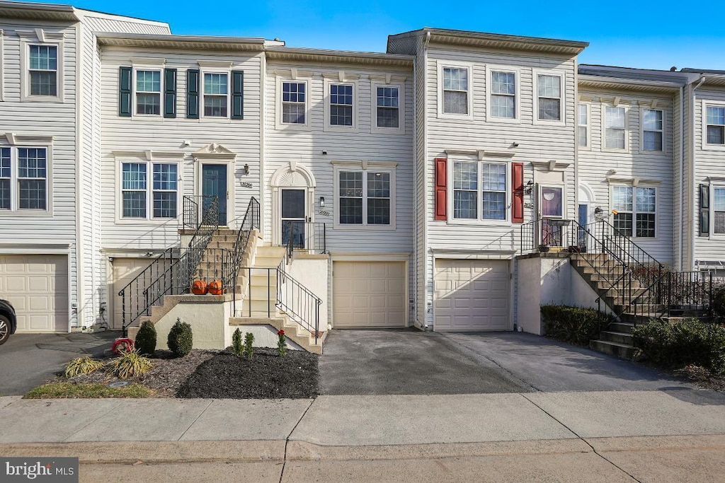 multi unit property featuring stairway, an attached garage, and driveway