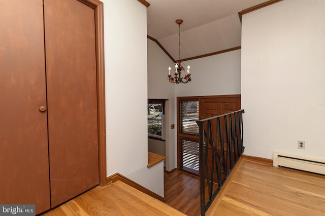 foyer entrance featuring wood finished floors, baseboards, lofted ceiling, an inviting chandelier, and a baseboard heating unit