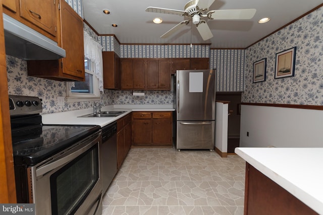 kitchen featuring under cabinet range hood, stainless steel appliances, a wainscoted wall, and wallpapered walls