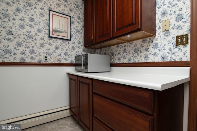 kitchen with baseboard heating, wallpapered walls, light countertops, and a wainscoted wall