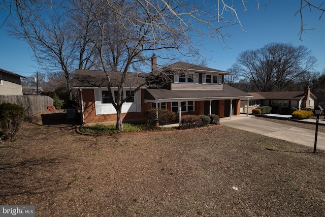 view of front of home with driveway, fence, a garage, brick siding, and a chimney