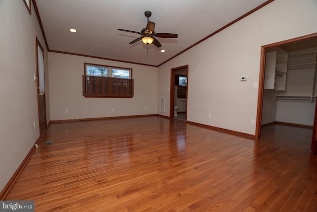 interior space with baseboards, lofted ceiling, wood finished floors, and crown molding