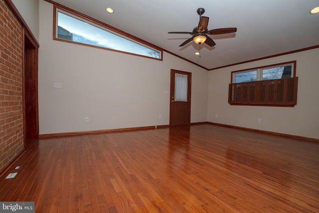 unfurnished room with lofted ceiling, crown molding, light wood-type flooring, and brick wall