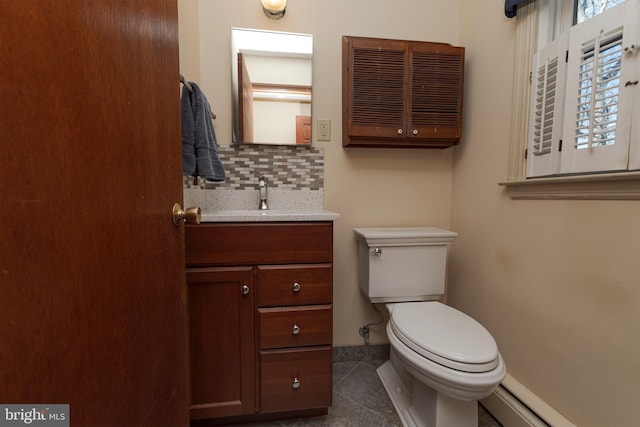 bathroom featuring tile patterned floors, toilet, a baseboard heating unit, decorative backsplash, and vanity