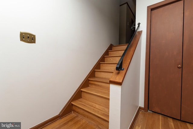 staircase featuring wood finished floors and baseboards