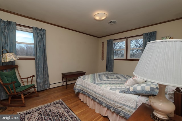 bedroom featuring visible vents, a baseboard radiator, wood finished floors, and ornamental molding