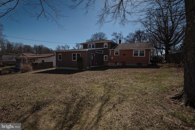 rear view of house featuring brick siding, a chimney, and fence