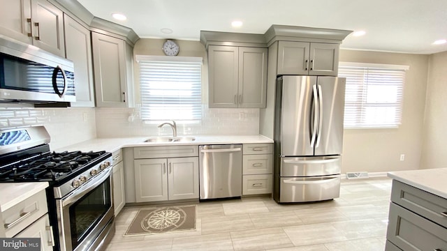 kitchen featuring visible vents, light countertops, gray cabinets, stainless steel appliances, and a sink