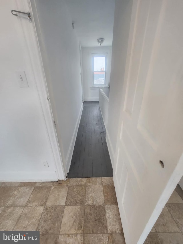 hallway with stone finish flooring and baseboards