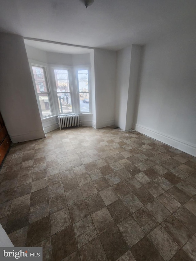 spare room featuring baseboards and radiator