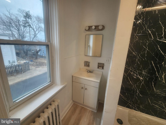 bathroom featuring vanity, radiator heating unit, and wood finished floors