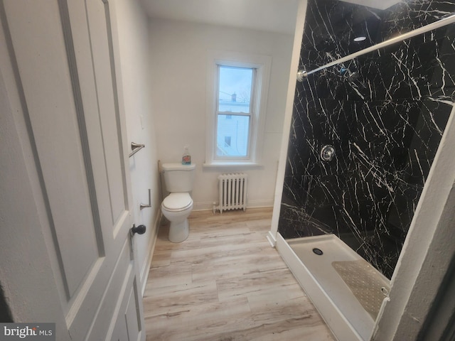 full bath with a marble finish shower, toilet, radiator heating unit, and wood finished floors