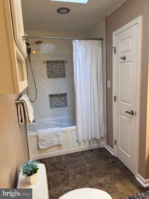 bathroom with toilet and shower / bath combo with shower curtain