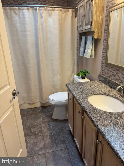 bathroom with tasteful backsplash, toilet, and vanity