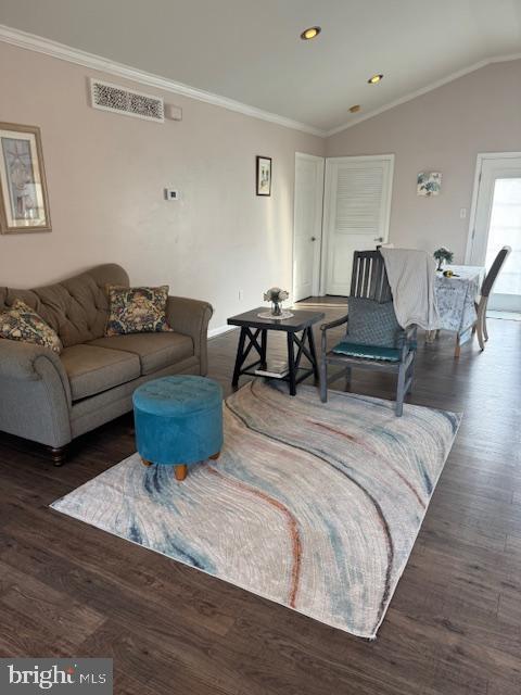 living room with visible vents, wood finished floors, crown molding, and vaulted ceiling