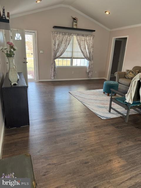 living area featuring lofted ceiling, wood finished floors, baseboards, and ornamental molding