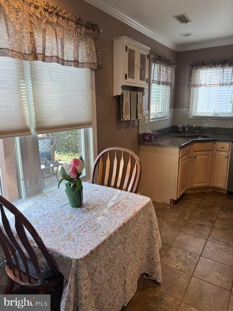 dining area featuring visible vents, a healthy amount of sunlight, and crown molding