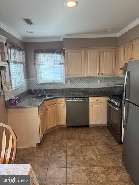 kitchen with visible vents, a sink, dark countertops, appliances with stainless steel finishes, and crown molding