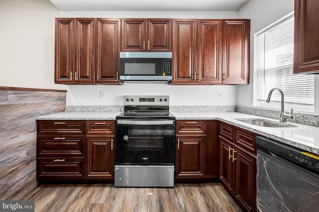 kitchen with light stone counters, dark wood-style flooring, appliances with stainless steel finishes, and a sink