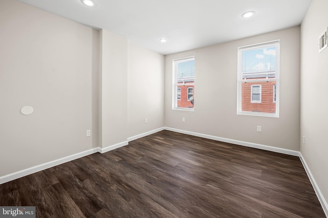 spare room featuring recessed lighting, baseboards, and dark wood-type flooring