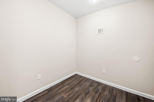 spare room with dark wood finished floors, visible vents, and baseboards