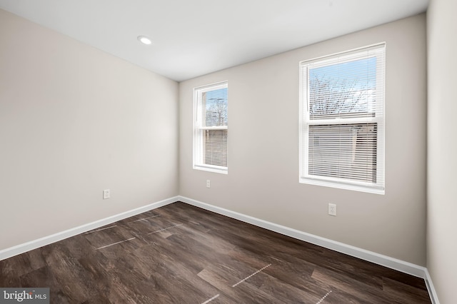 unfurnished room with baseboards and dark wood-type flooring